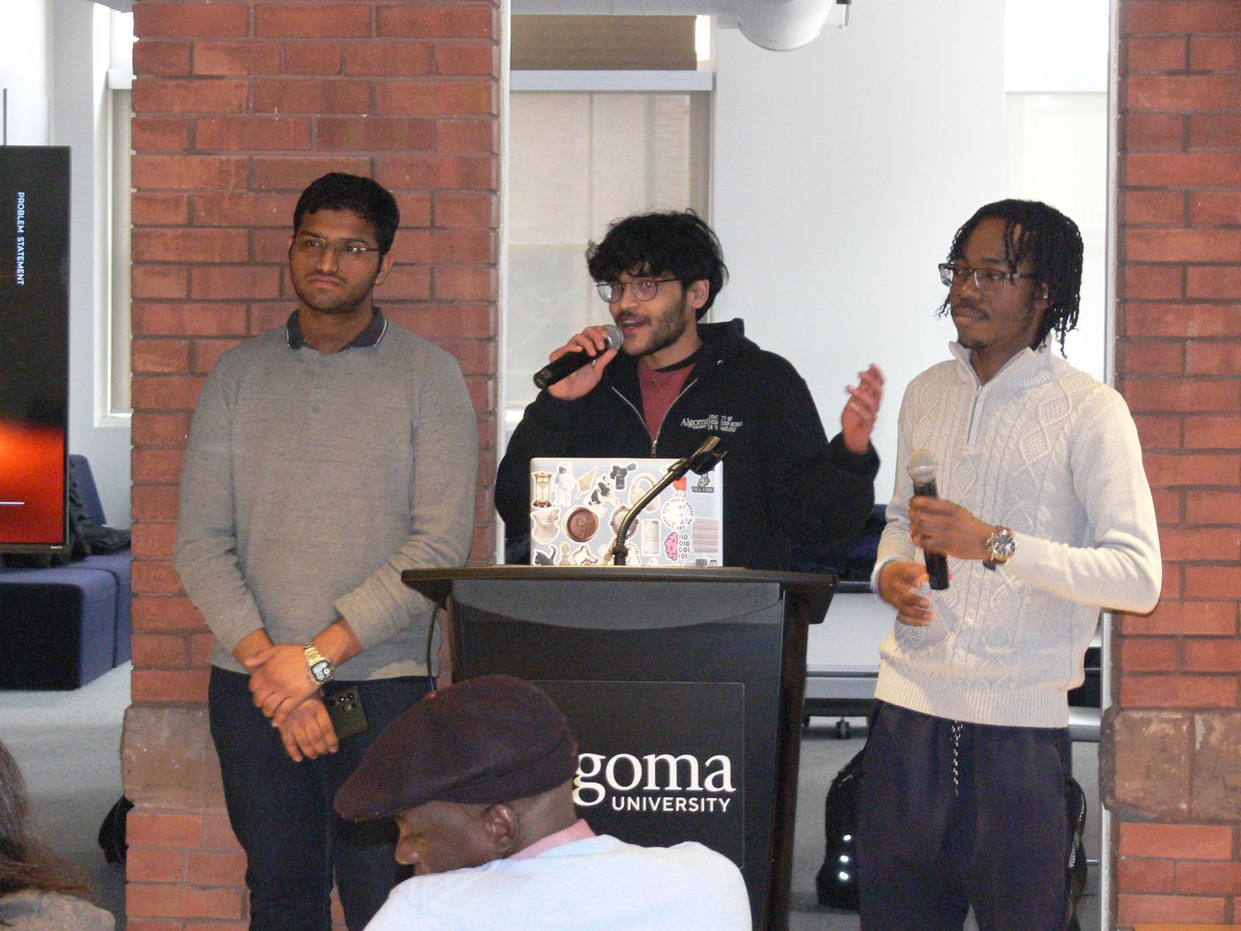 Three hackers presenting their project at the podium at ThunderHacks, March 2026